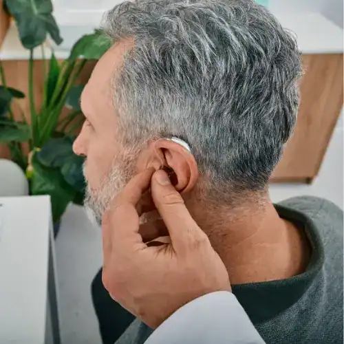 audiologist adjusting hearing aid during appointment